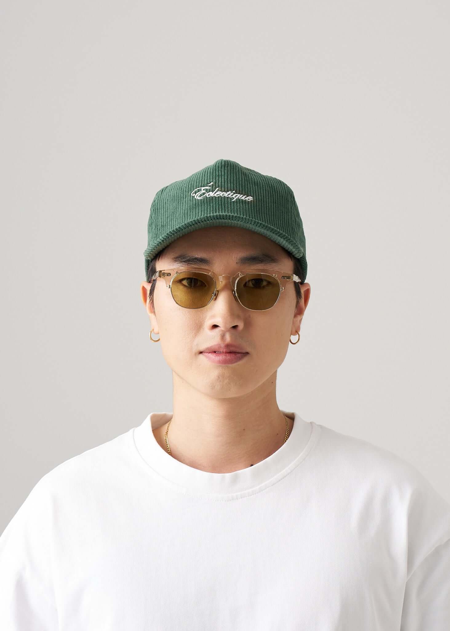 Corduroy script logo snapback hat worn by a model with sunglasses and a white t-shirt.