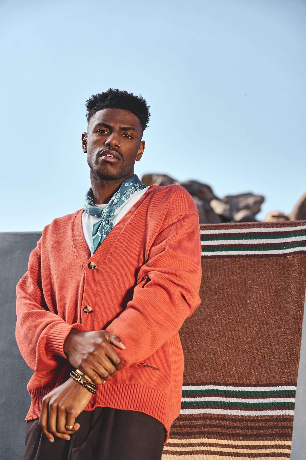 Male model wearing orange v neck cardigan in Sunburst outdoors