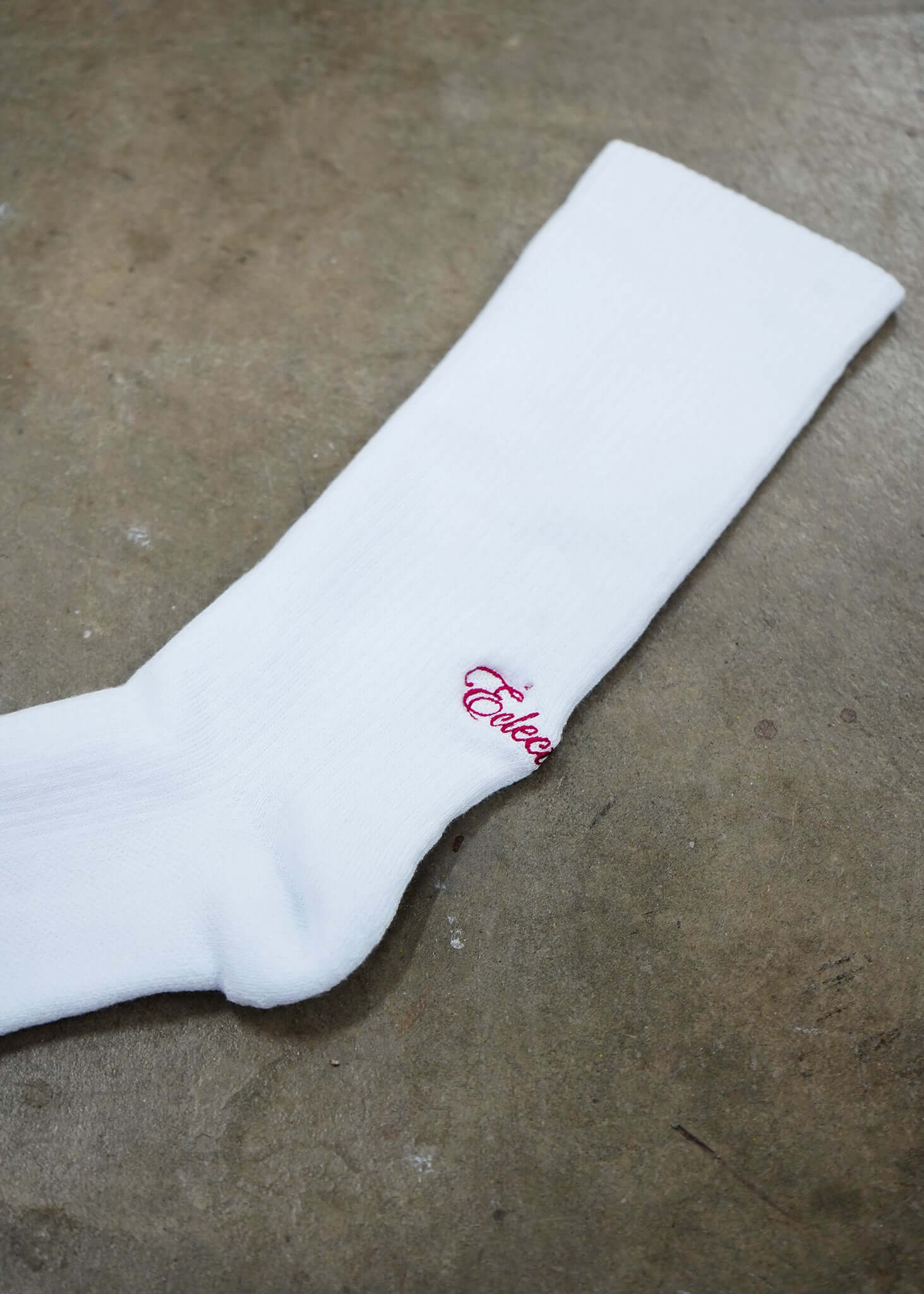 White logo socks featuring a red script logo by Éclectique, crafted from premium combed cotton for comfort.