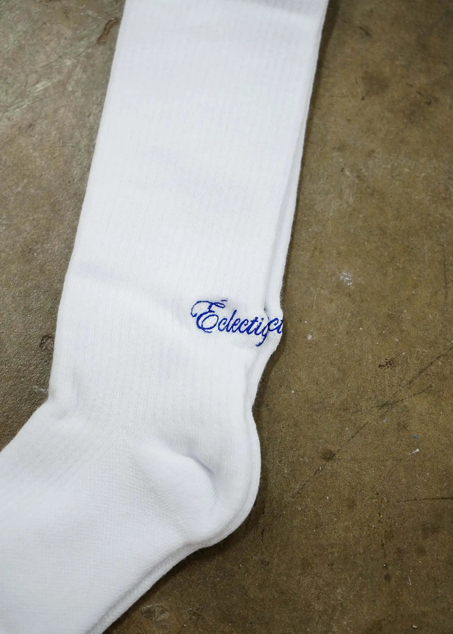 White logo socks featuring Éclectique’s blue script logo on a soft white cotton fabric.