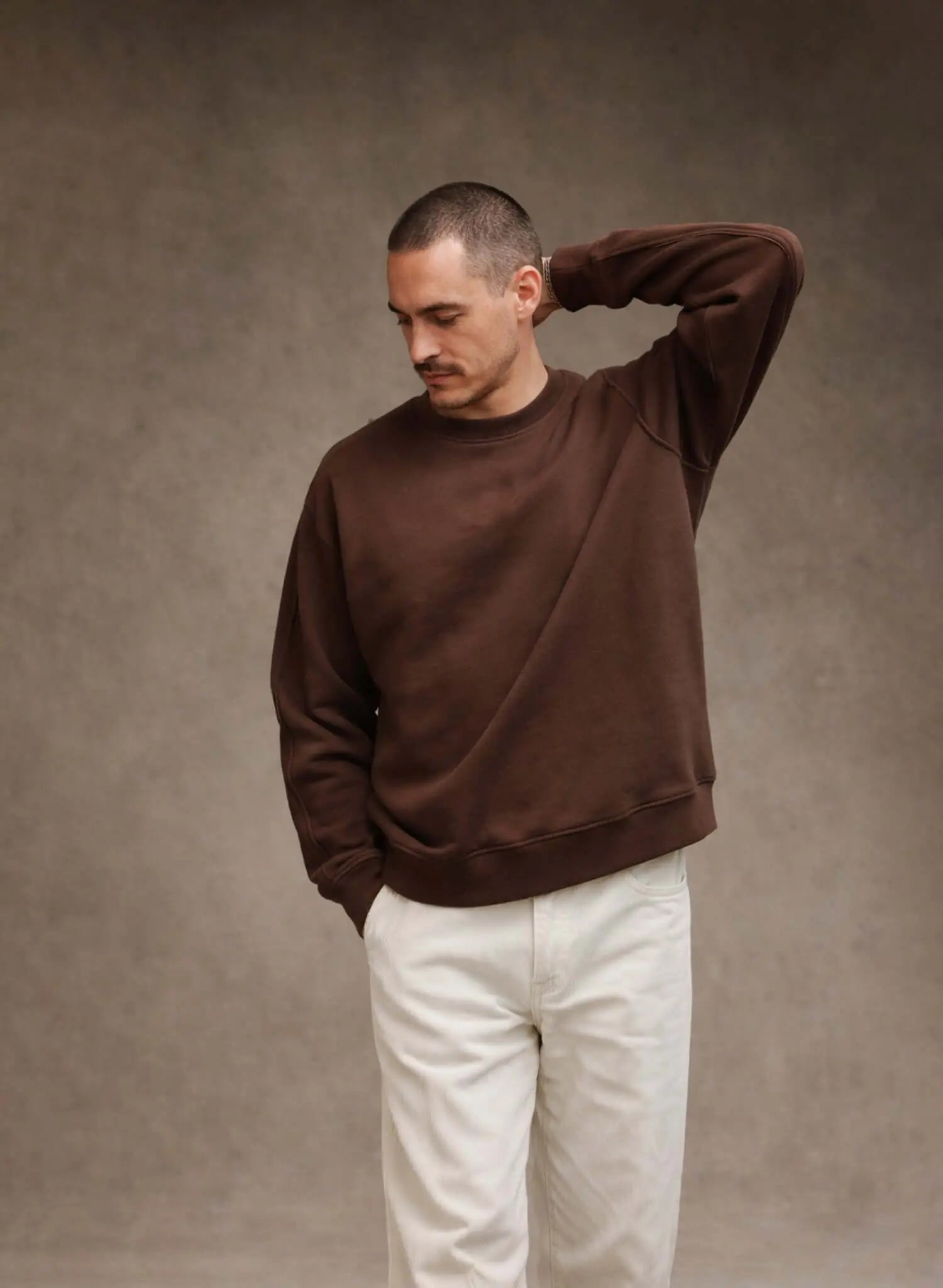 Model wearing a brown French Terry crewneck sweatshirt with white pants, showcasing style and comfort.