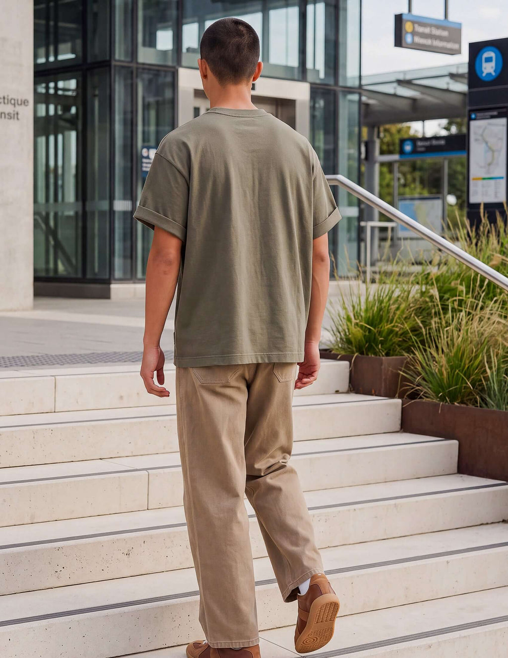 Men's Olive Cotton T-shirt worn by a man walking down steps in a modern urban setting.