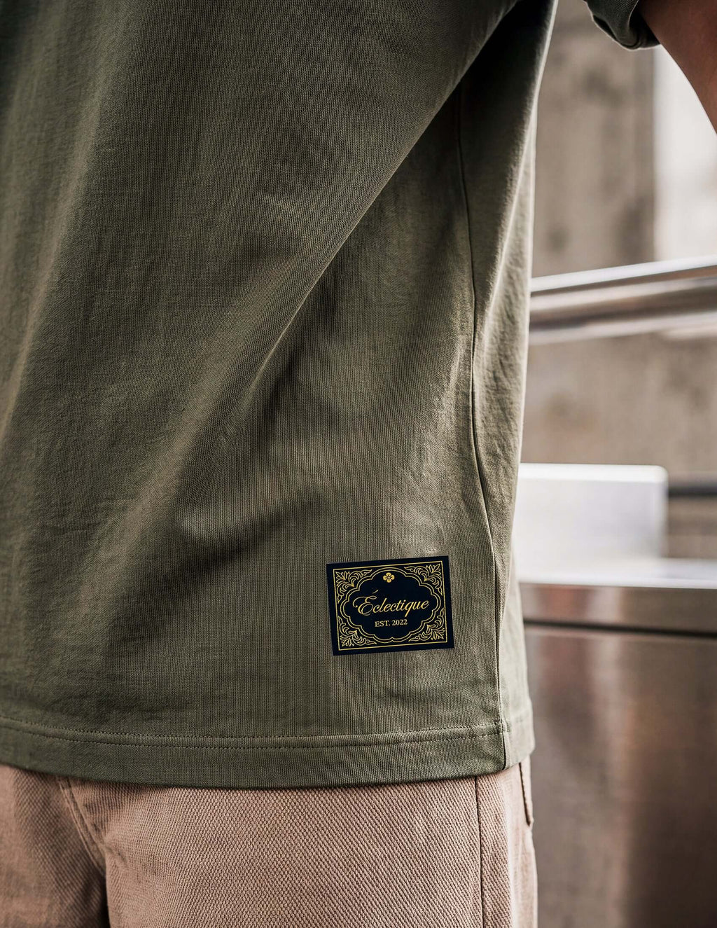 Men's Olive Cotton T-shirt with Éclectique logo tag on the hem, showcasing relaxed fit and quality craftsmanship.