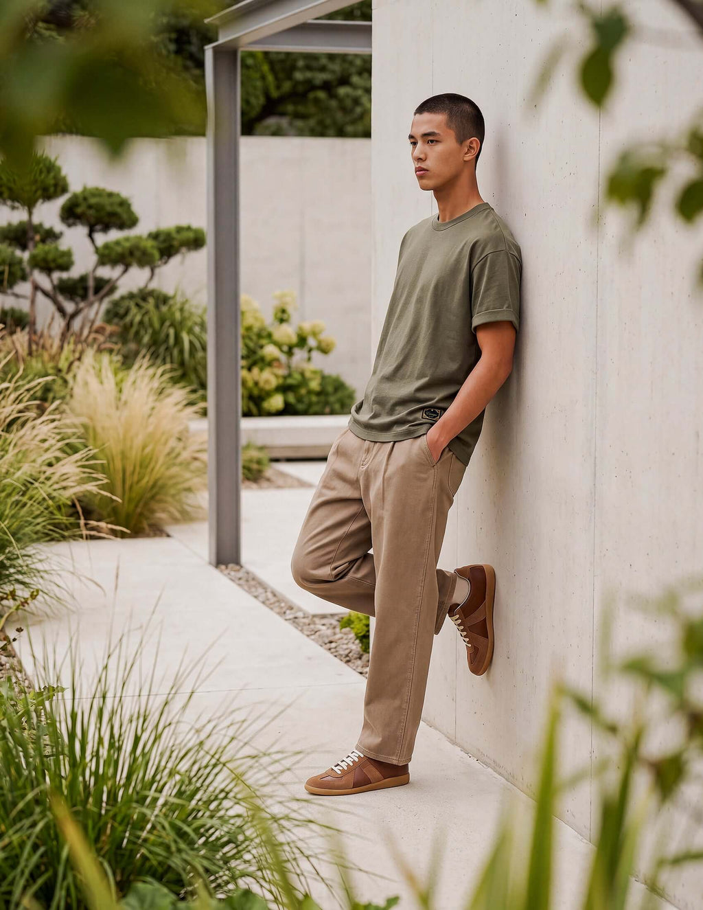 Men's Olive Cotton T-shirt being worn outdoors against a modern concrete wall, showcasing relaxed style.