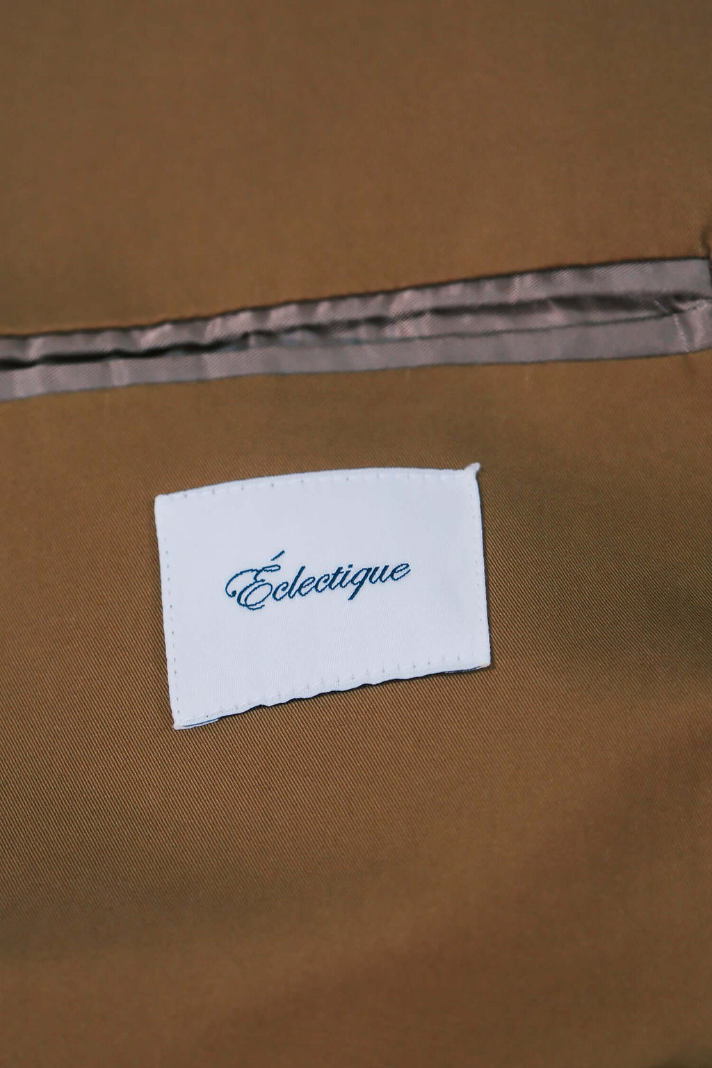 Éclectique label on a men's camel trench coat in rich camel fabric.