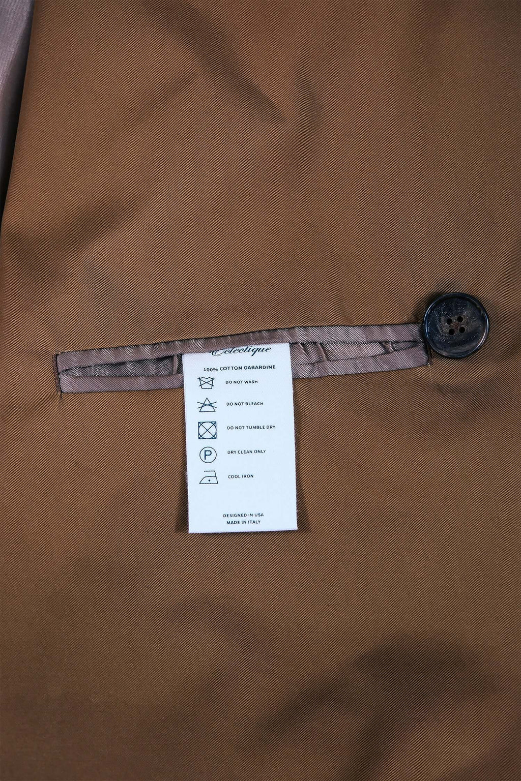 Close-up of the label and button detail on the interior of a men's camel trench coat.
