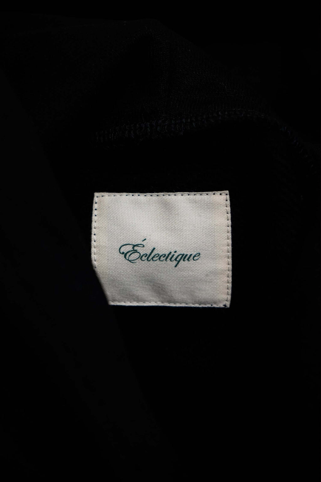 Éclectique label on a midweight cotton hoodie, showcasing the brand's script logo on the inside fabric.