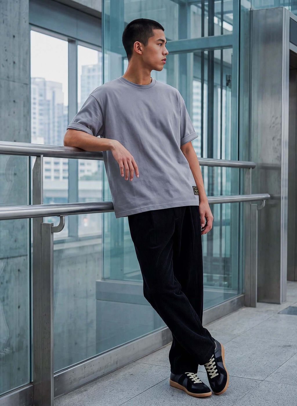 Model wearing Men's Dolphin Grey Cotton T-shirt paired with black pants, showcasing a relaxed fit in an urban setting.