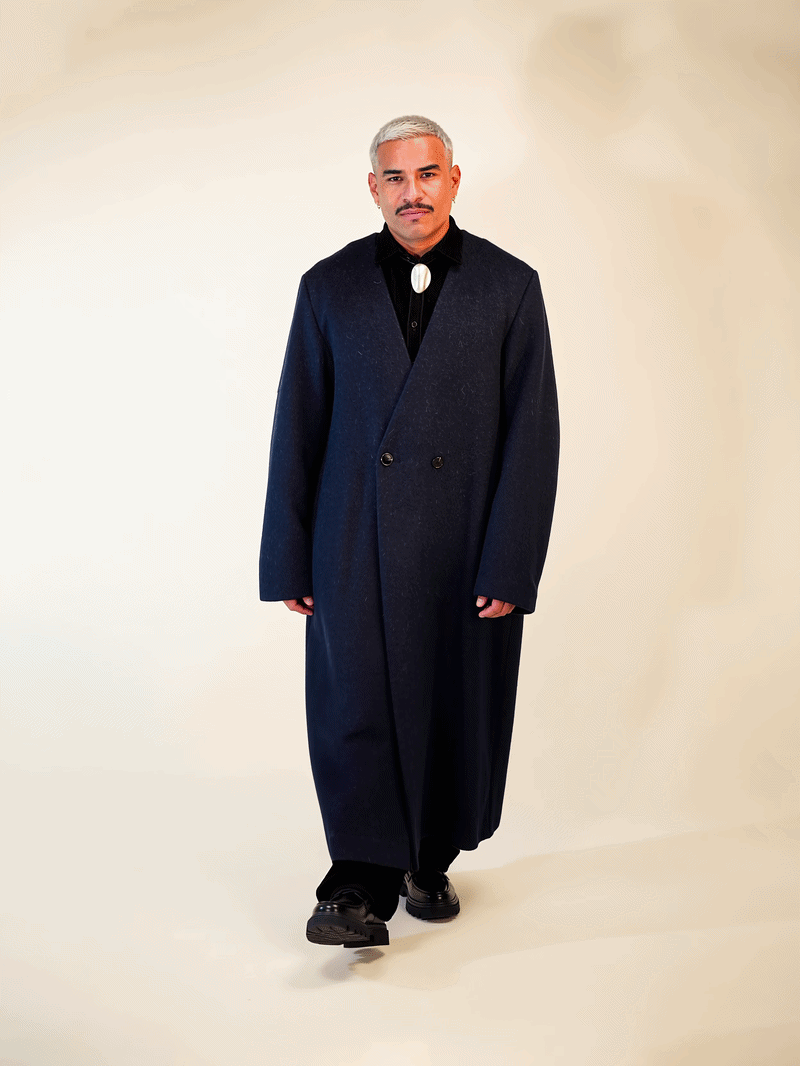 Men's navy collarless long coat – Kanso worn by a model, featuring an oversized silhouette and deep V-shaped neckline.