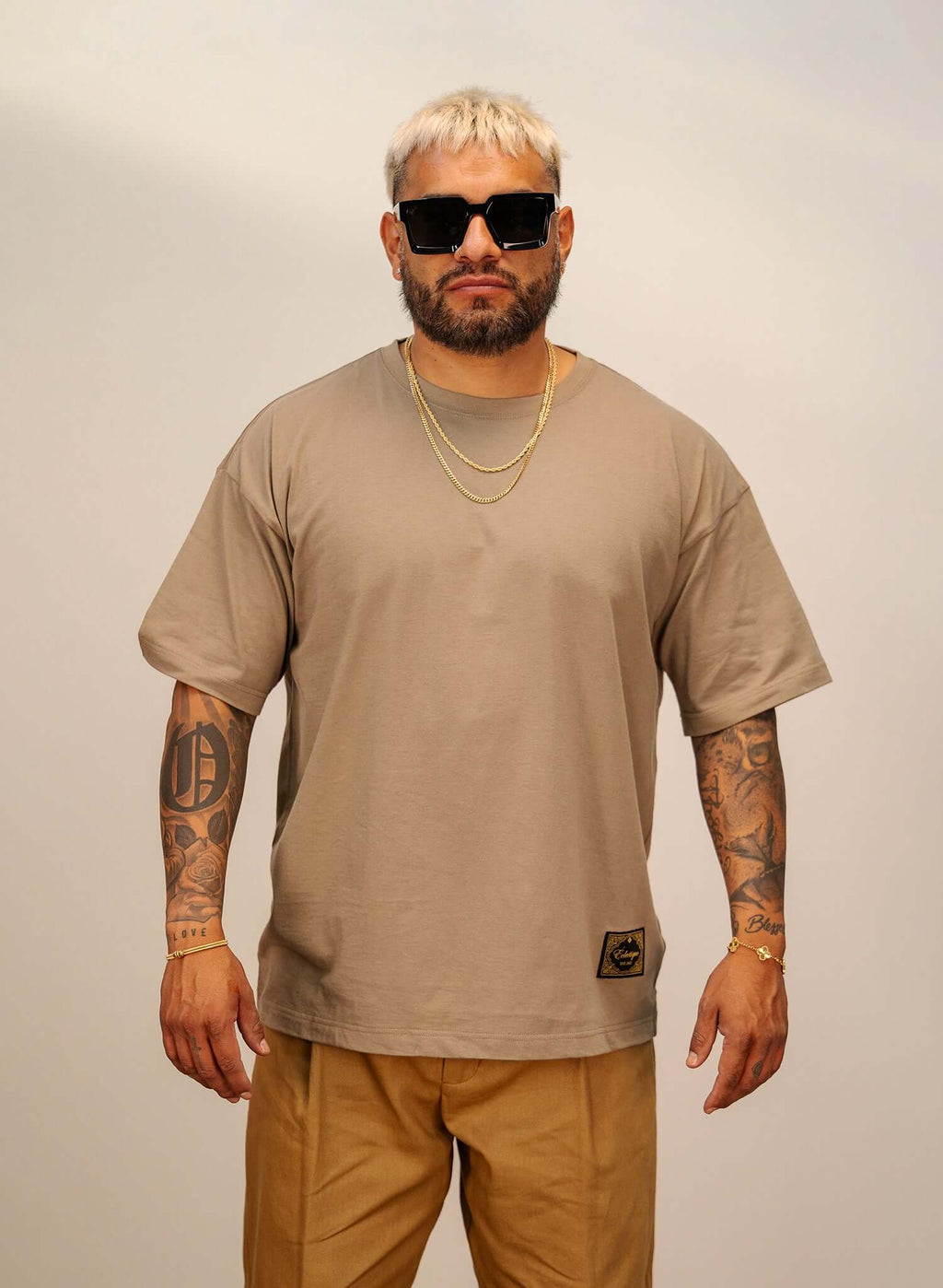 Men's Sand Cotton T-shirt, a relaxed fit essential worn by a model with sunglasses and chain accessories.