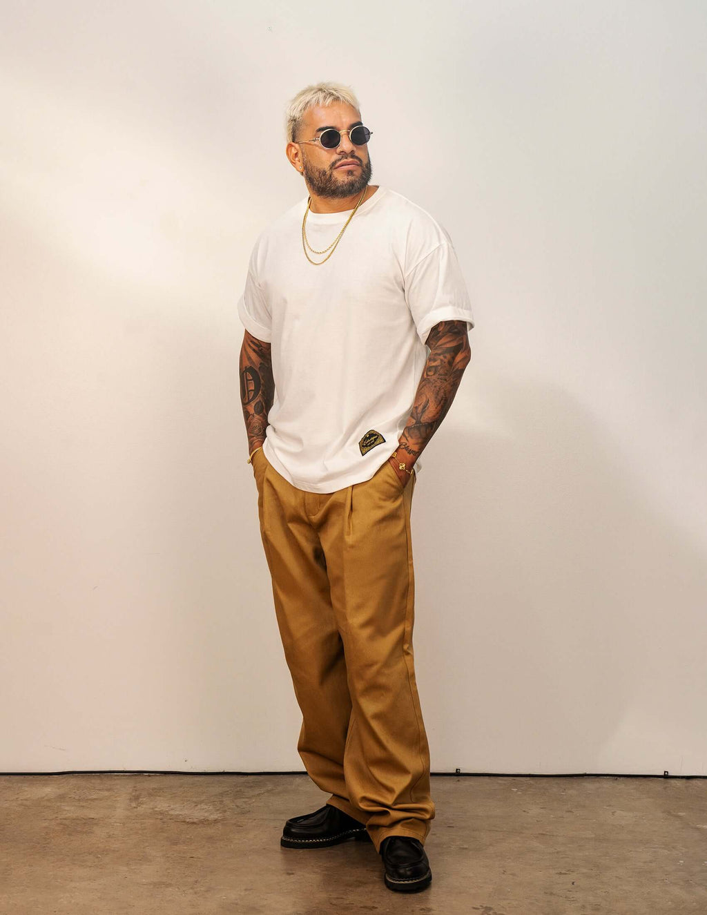 Man wearing a Men's White Cotton T-shirt standing confidently, styled with sunglasses and relaxed pants.