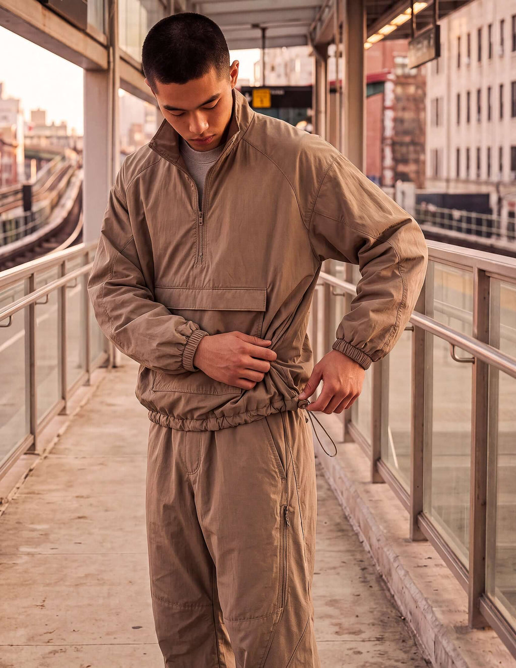 Man adjusting the hem of the Waypoint Lightweight Anorak in Clay, a technical windbreaker designed for movement.