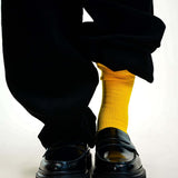 Yellow crew socks paired with black loafers and pants, showcasing a stylish contrast.