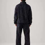 Back view of a model wearing black leopard fleece pants and a matching fleece jacket.