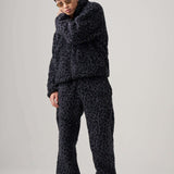 Model wearing black leopard fleece pants and matching jacket, showcasing a chic and comfortable outfit.