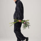 Model wearing black Leopard fleece pants with a matching jacket, holding flowers, showcasing casual style.