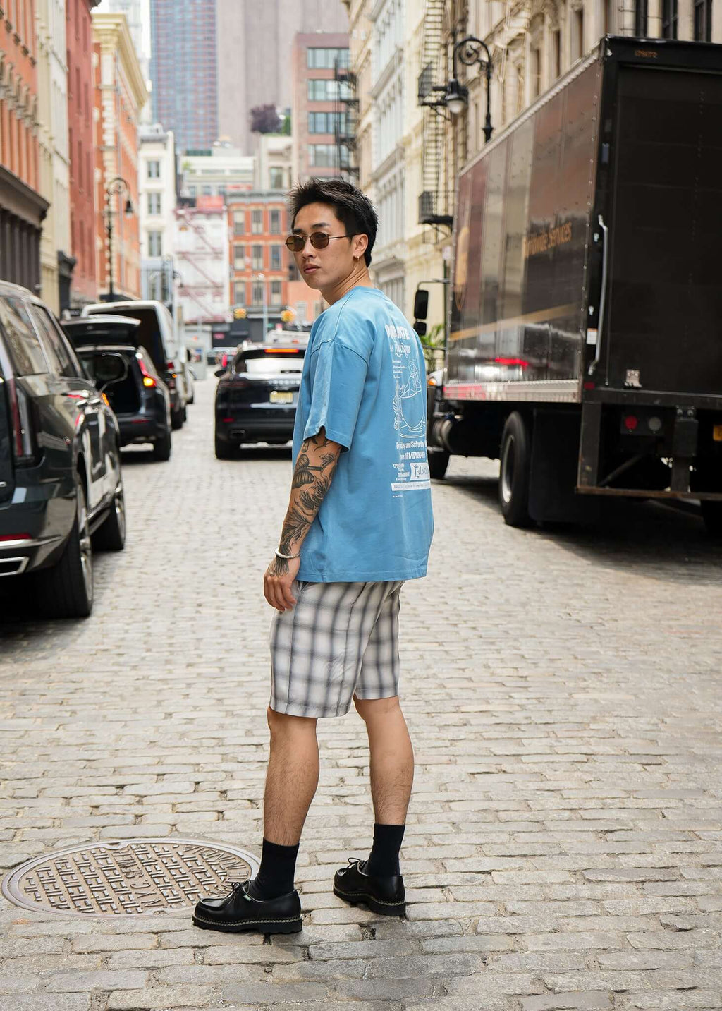 Man wearing Carolina Blue Date Night T-shirt with plaid shorts in a trendy urban street setting.
