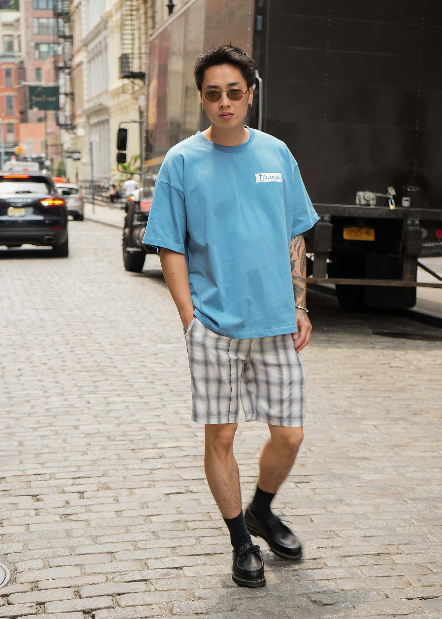 Man wearing Carolina Blue Date Night T-shirt with plaid shorts on a city street.