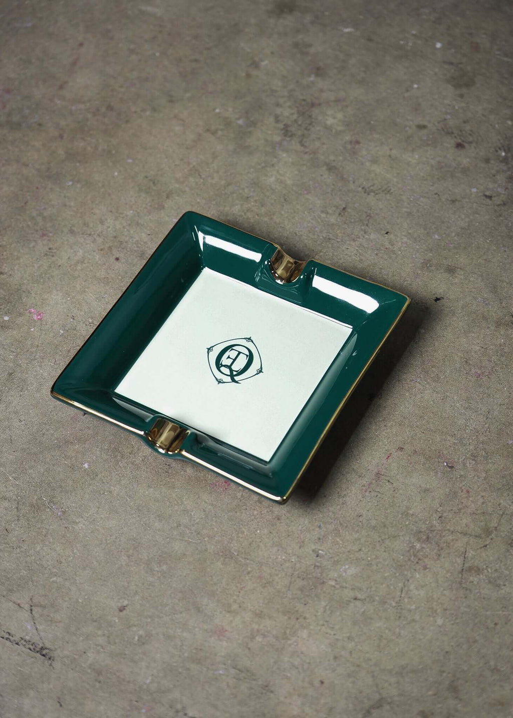 Ceramic Cigar Ashtray with gold trim and monogram logo on a green square tray.
