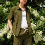 Model wearing designer men's casual shorts made from 100% nylon in olive green with cream drawstring on a sunny day.