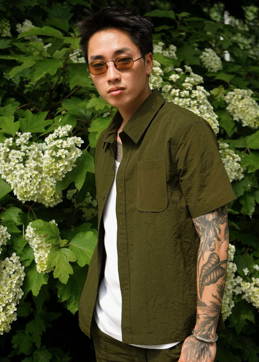 Designer Short sleeve casual shirt in olive worn by a model among white flowers, showcasing refined style and comfort.
