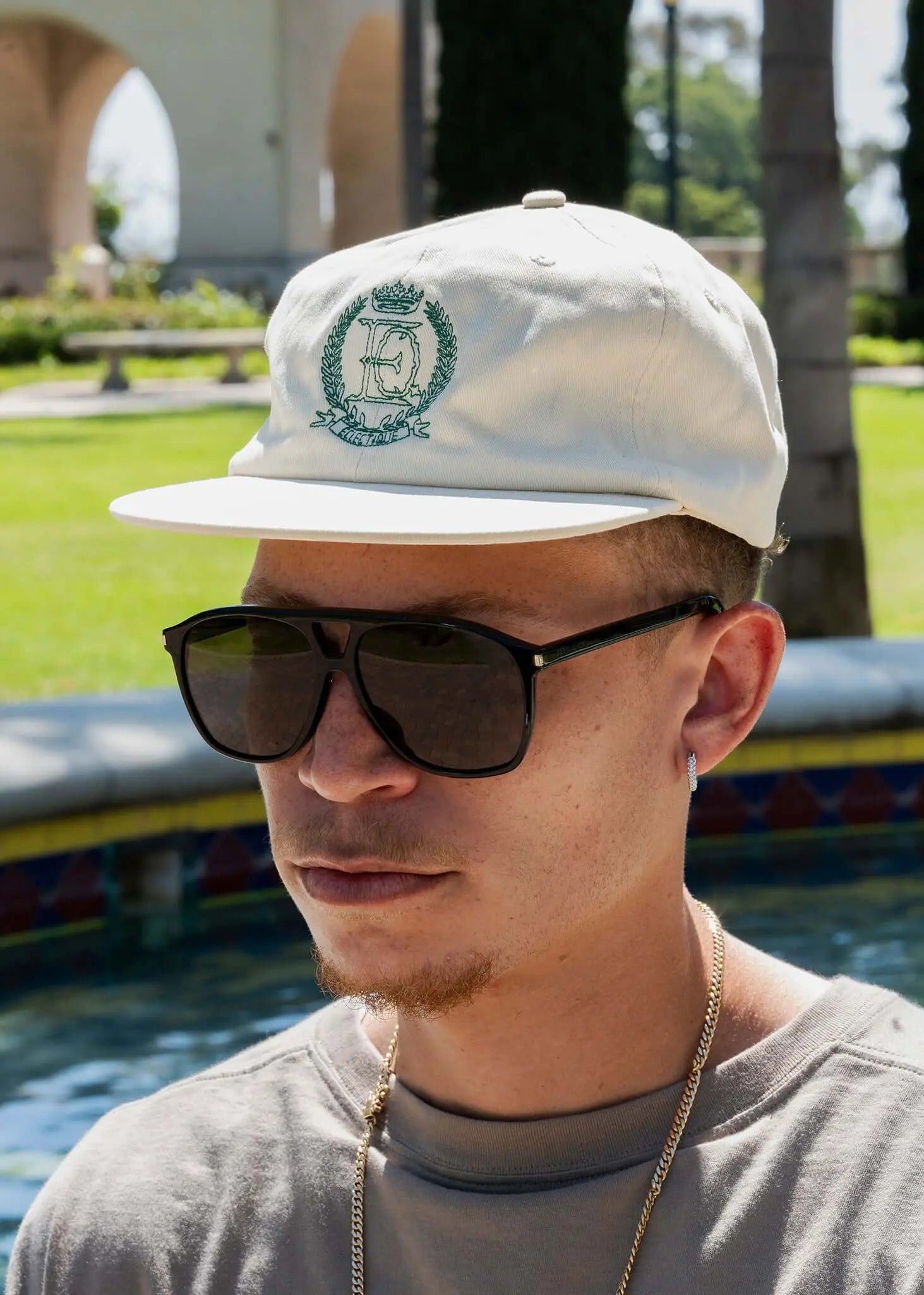 Éclectique Crest embroidered dad hat worn by a man with sunglasses in a sunny outdoor setting.