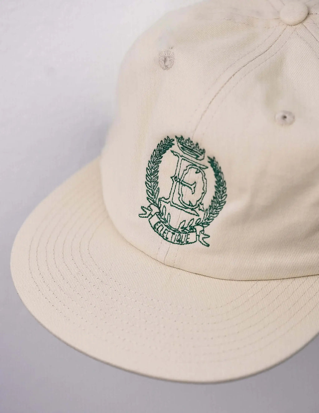Side view of Éclectique crest embroidered dad hat in off-white cotton
