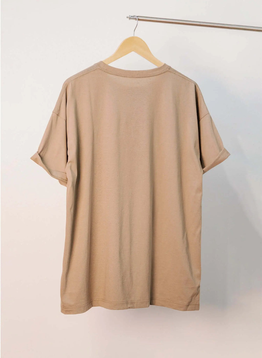 Men's sand cotton t-shirt displayed hanging on a clothing rack, showing the back view and relaxed fit.