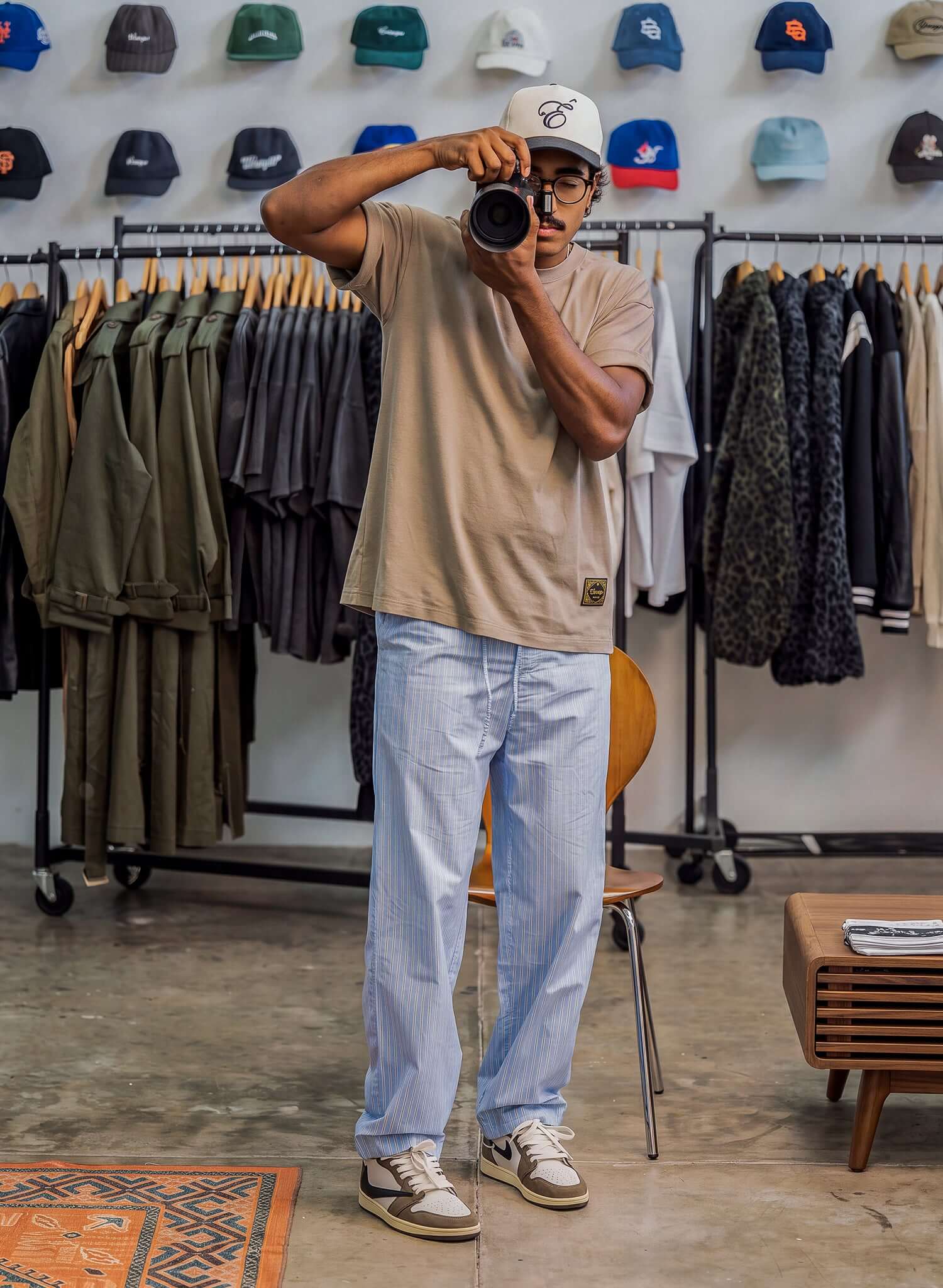 Essential Cotton T-shirt in sand worn by a person taking a photo in a stylish retail environment.