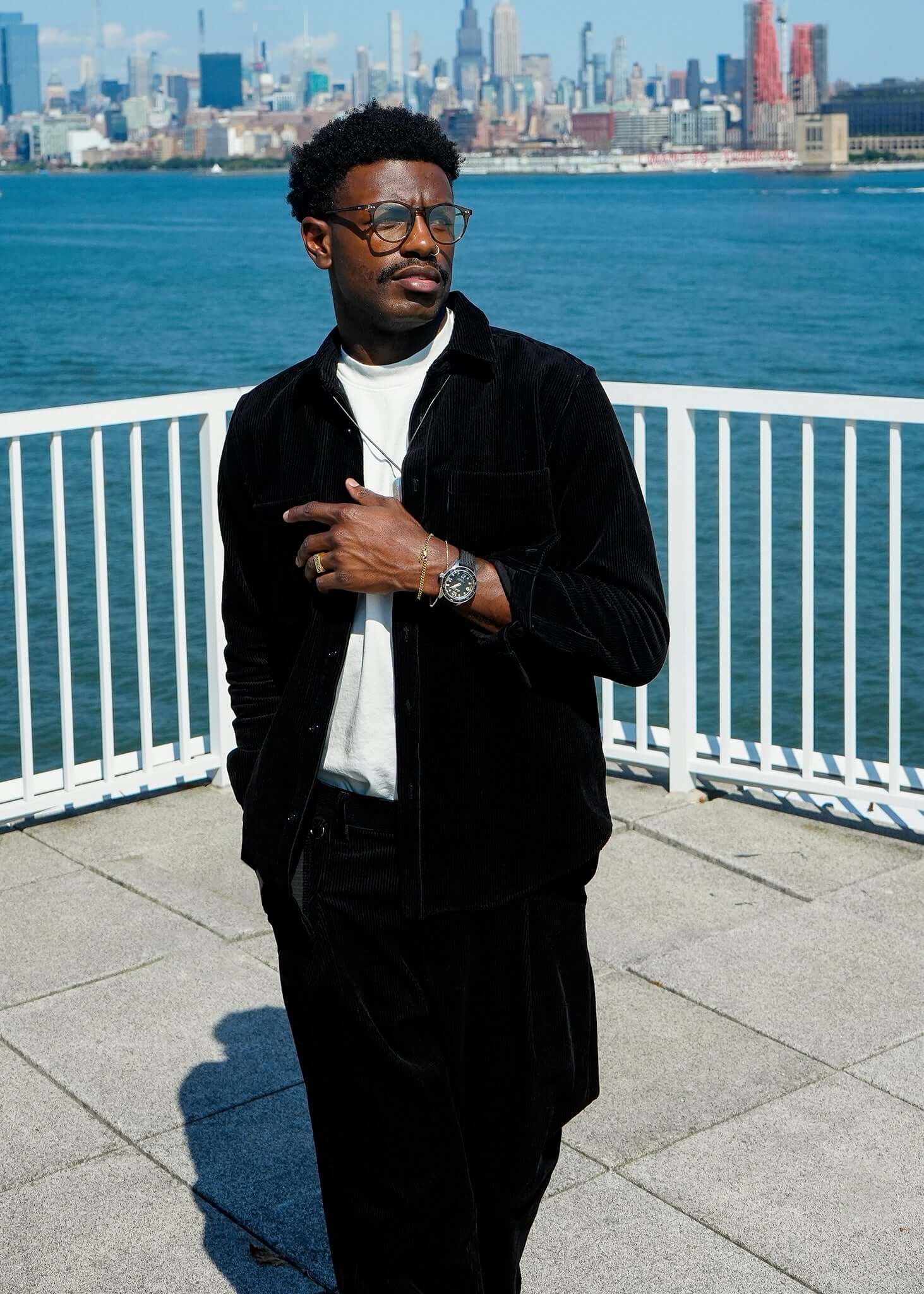 Man wearing black Mercer Corduroy Button-up Shirt with city skyline by the water.
