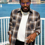 Man wearing a Mercer Plaid Cotton Button-Up Shirt with sunglasses by the water, showcasing modern menswear style.