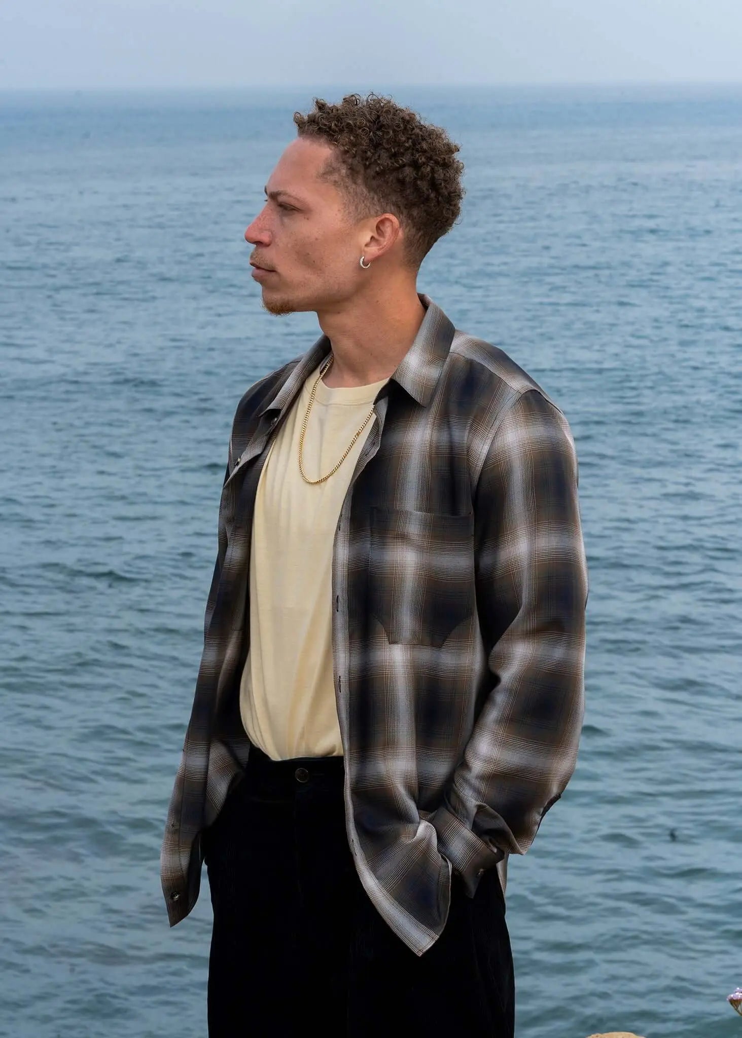 Man wearing a Plaid Cotton Button-up Shirt by Mercer, standing by the water, with a soft, structured feel.