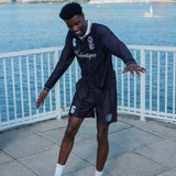 Model showcasing performance soccer shorts by Éclectique near waterfront with city skyline in background.
