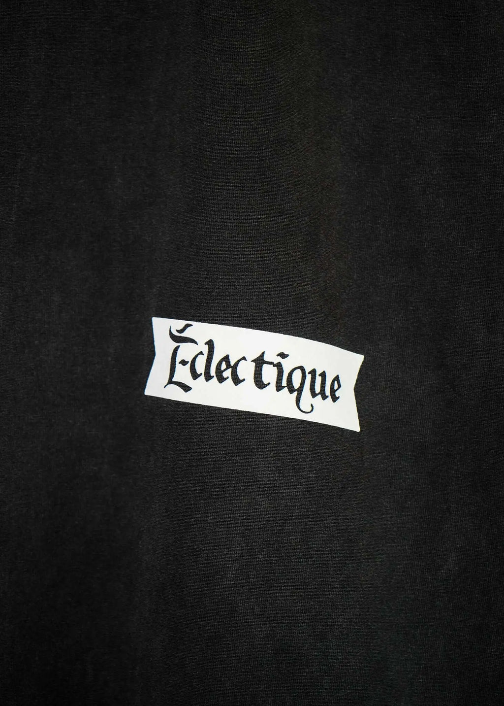 Close-up of Éclectique label on a black fabric, showcasing the brand name in stylish typography for rockets graphic t-shirt