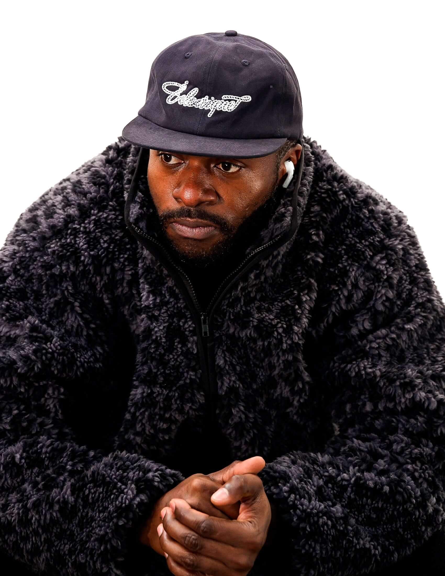 Man wearing a Rope Script Dad Hat and a fluffy black jacket, showcasing a relaxed style and modern fashion.