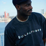 Model wearing a Seinfeld Vintage logo hat with an Éclectique t-shirt by the waterfront.