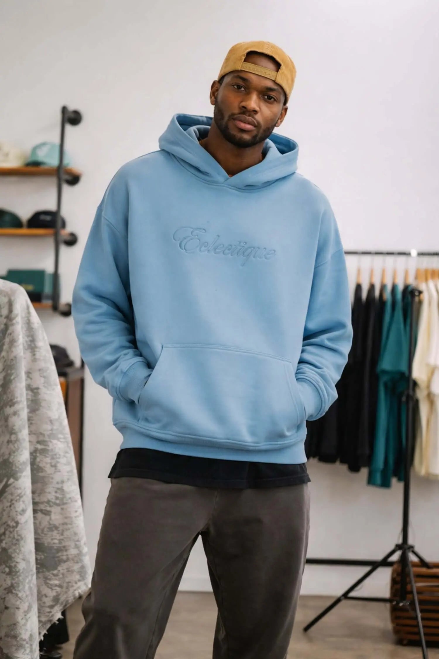 Lightweight terry hoodie with script logo in blue, featuring a relaxed fit and embroidered detail, styled on a man.