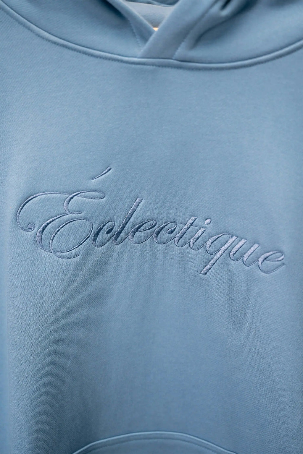 Close-up of Lightweight Terry Hoodie with Script Logo from Éclectique, showcasing soft fabric and embroidered logo detail.