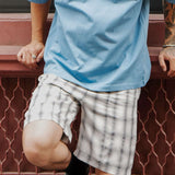 Model wearing monotone plaid shorts with blue shirt, showcasing elegance and casual style.