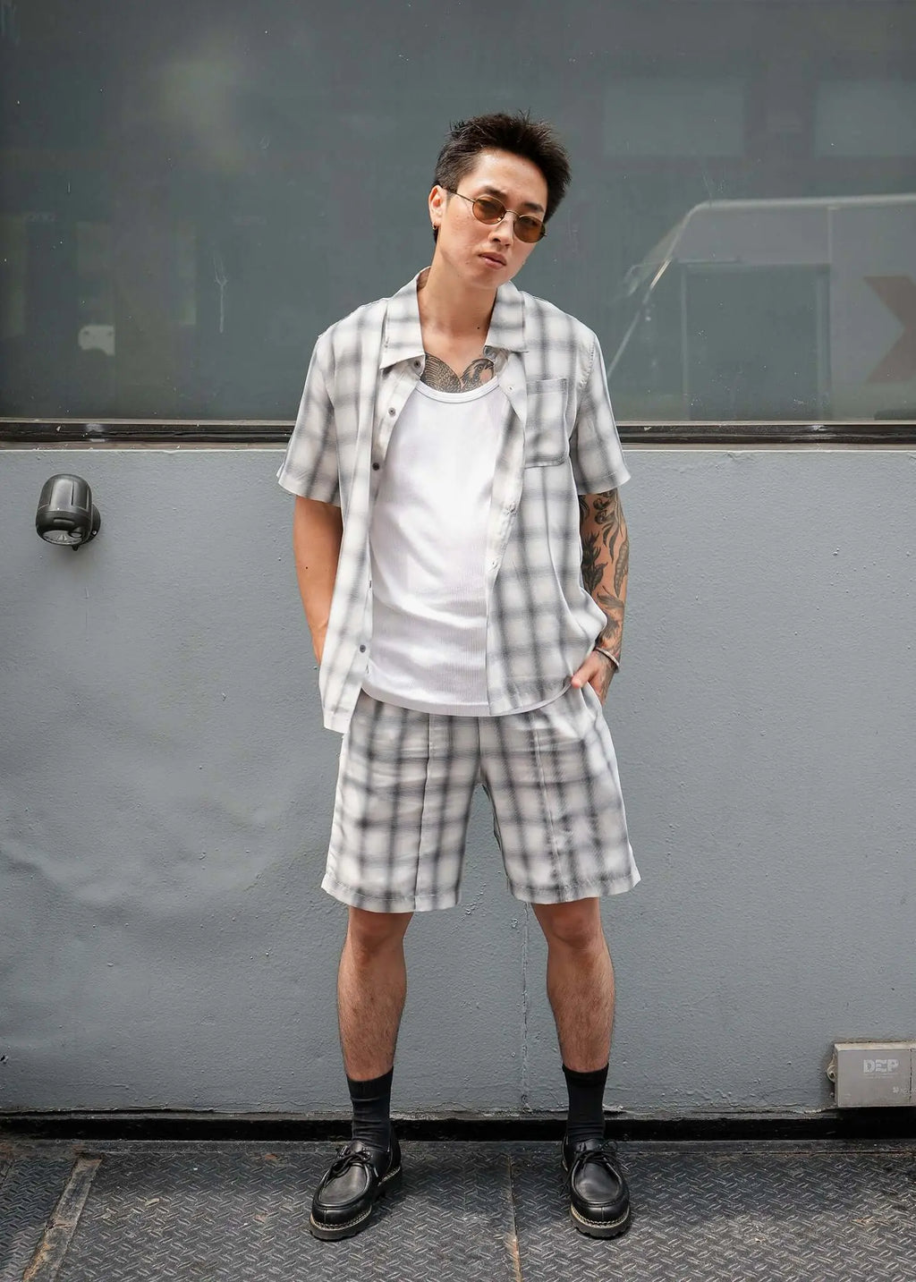Model wearing monotone plaid shorts with matching shirt, showcasing stylish and casual summer outfit.
