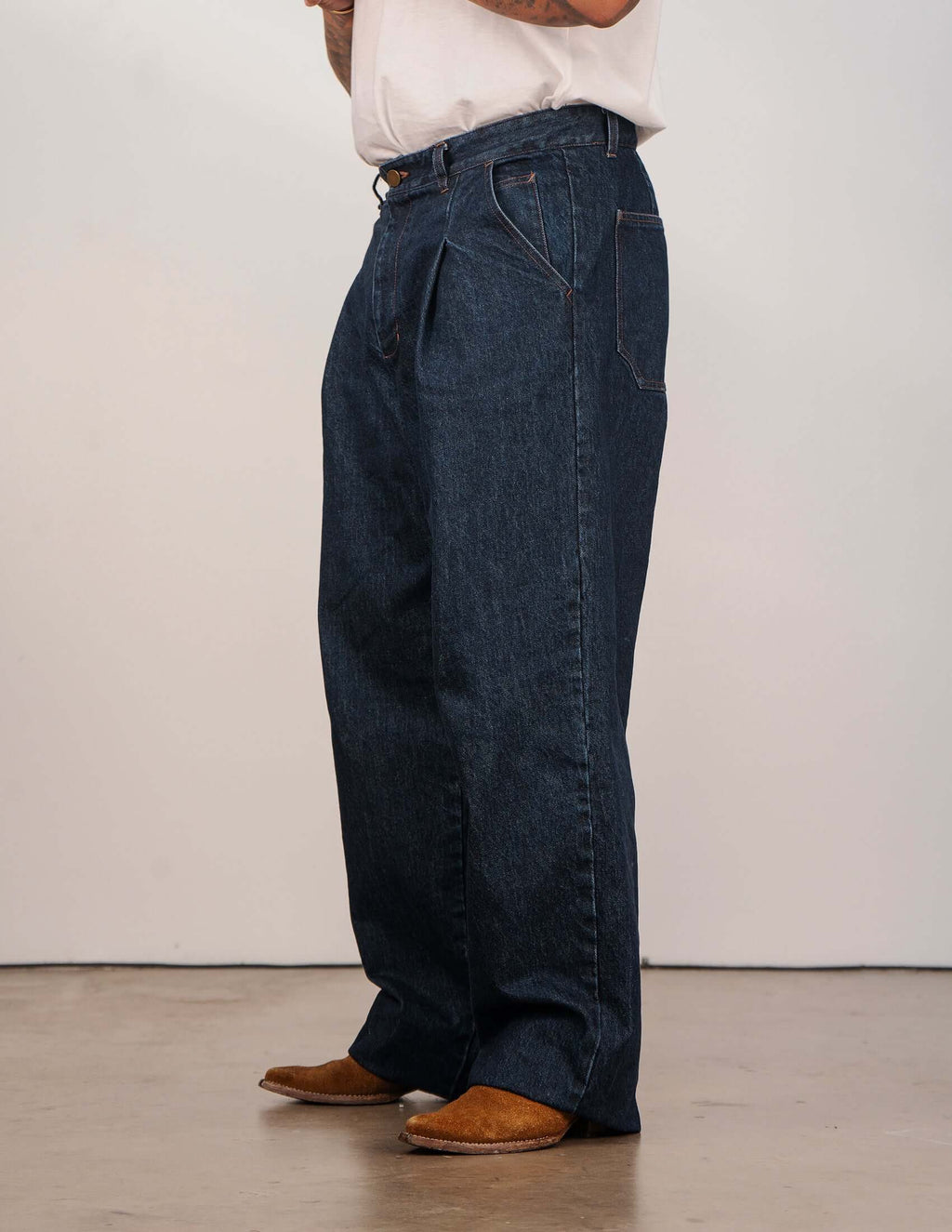 Side view of men's indigo pleated jeans, showcasing the relaxed wide-leg fit and front pleats.
