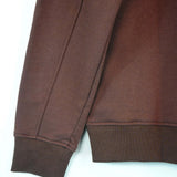Detail of the sleeve and cuff of a French Terry crewneck sweatshirt in rich brown color.