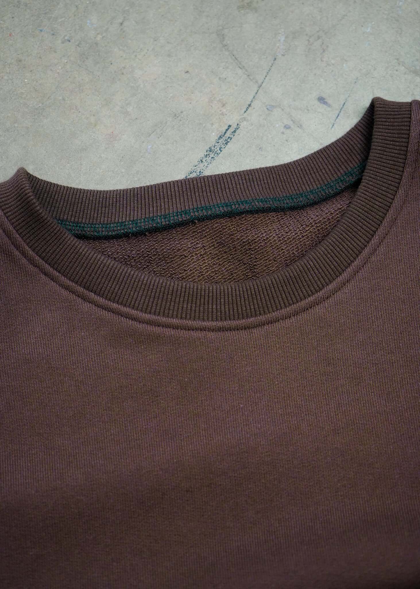 Close-up of the neckline of a French Terry crewneck sweatshirt in rich brown color.