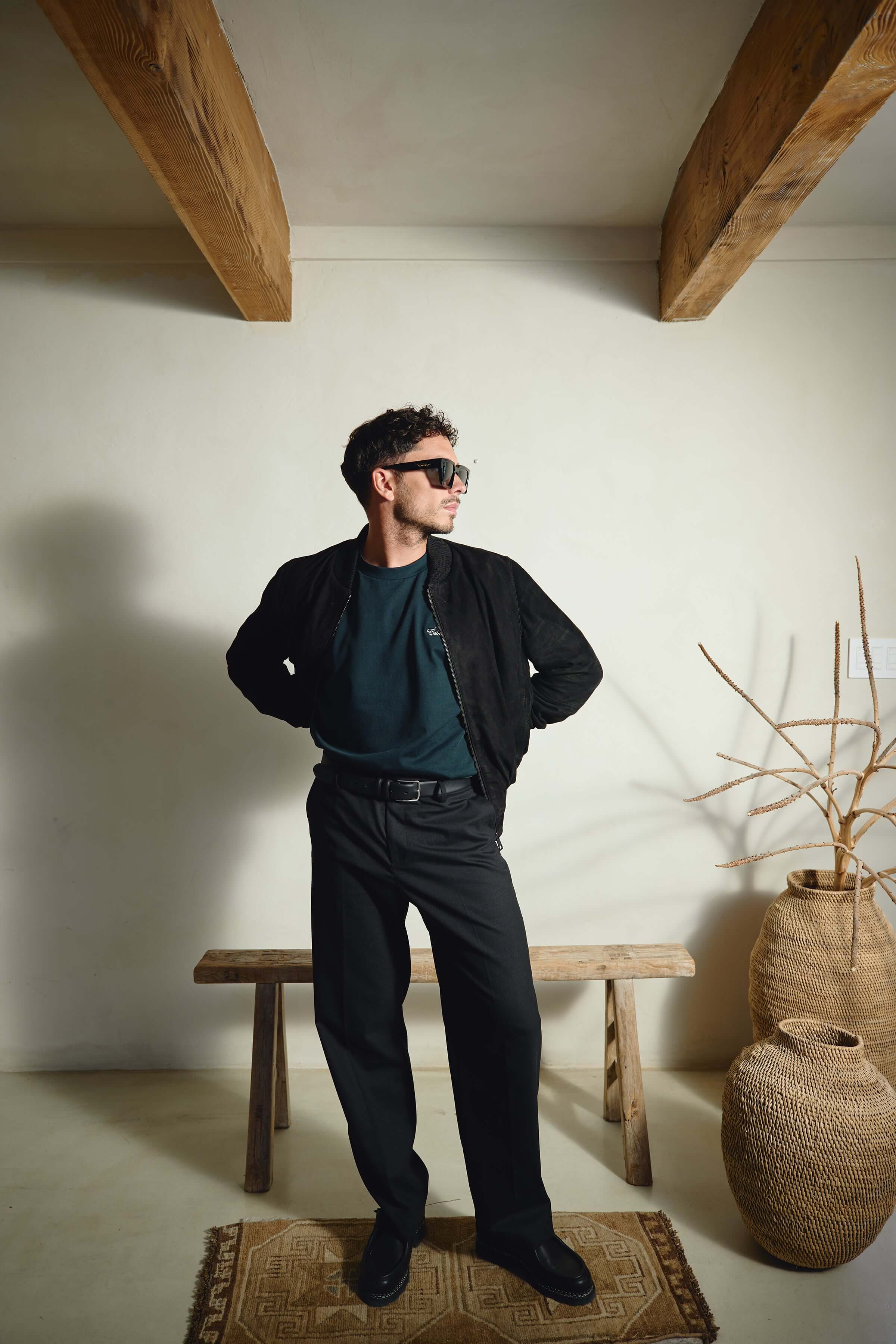 Model wearing Éclectique Italian suede bomber jacket in black with tailored trousers