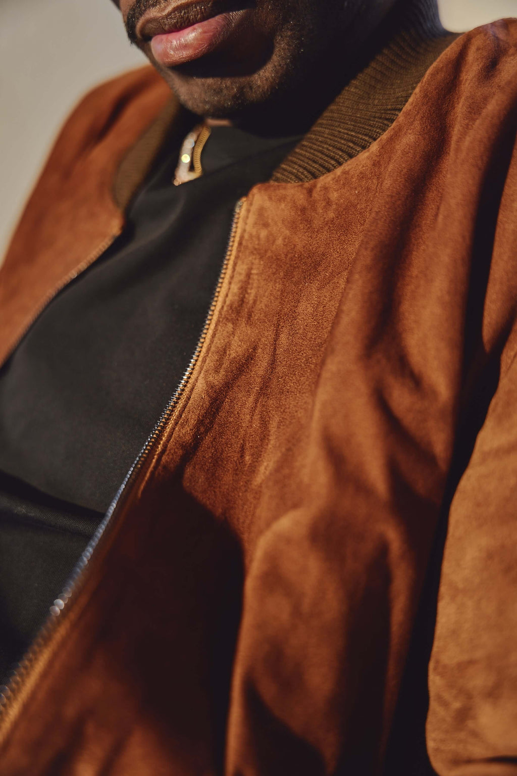 Close-up of brown Italian suede bomber jacket texture and zipper by Éclectique