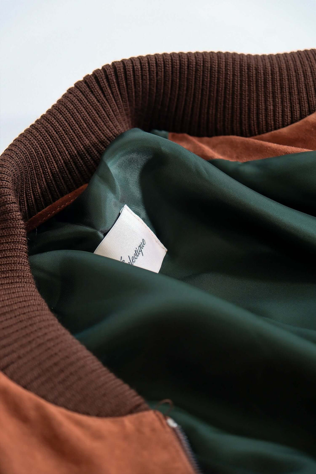 Interior lining and label detail of Éclectique Italian suede bomber jacket in brown