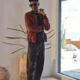 Model wearing Éclectique Italian suede bomber jacket in brown styled with black trousers