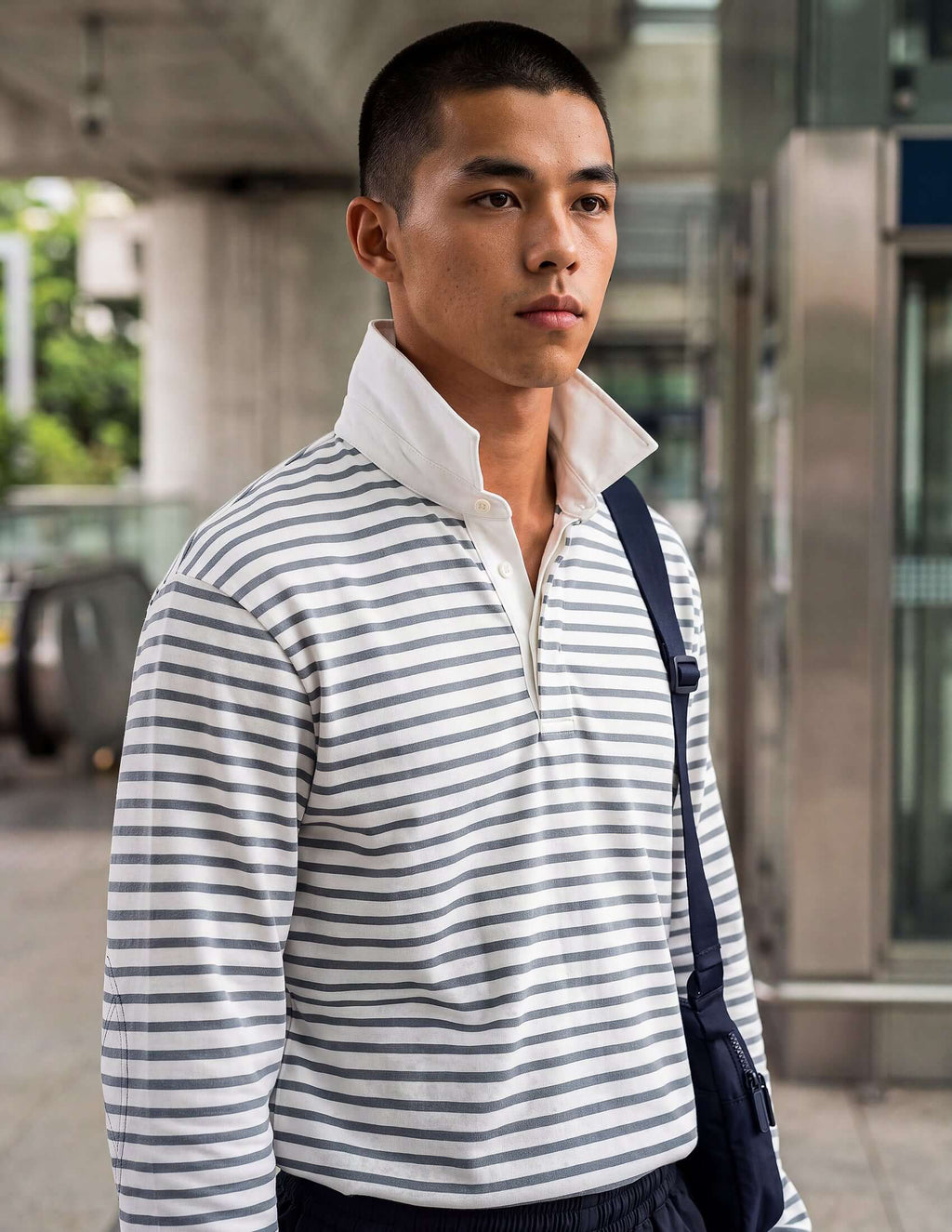 Men's striped long sleeve rugby shirt featuring blue-grey stripes and a white collar, modeled outdoors.