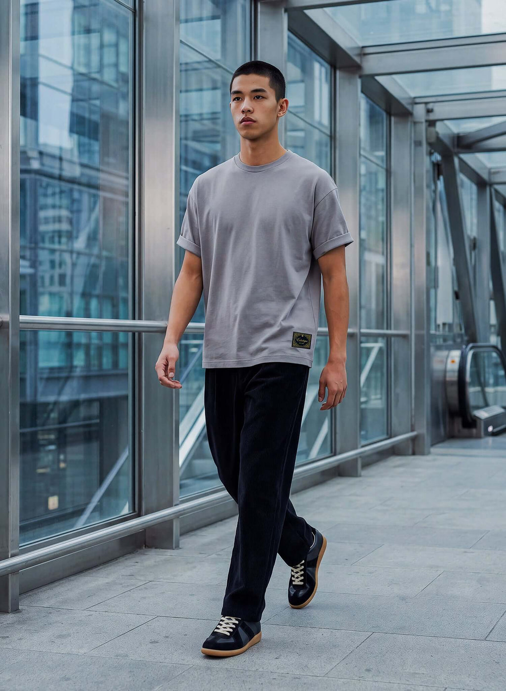 Men's Dolphin Grey Cotton T-shirt worn by a man walking in a modern urban setting.