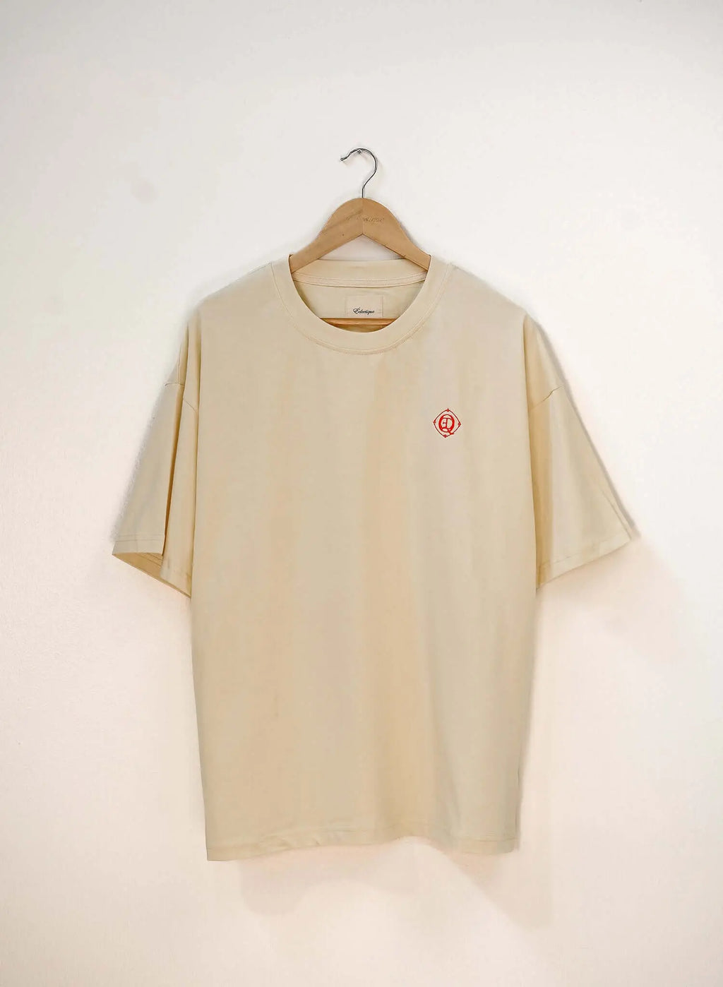 Monogram embroidered cotton t-shirt in French vanilla hanging on a wooden hanger.